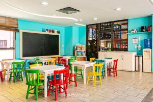 a classroom with tables and colorful chairs and a chalkboard at Studios modernos à beira-mar - Jurerê Beach Village JBVTOP in Florianópolis