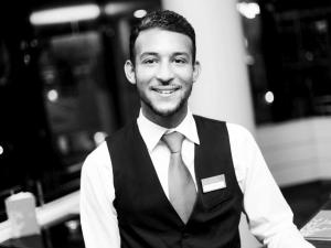 a man in a vest and tie is smiling at Mercure Hotel Hagen in Hagen