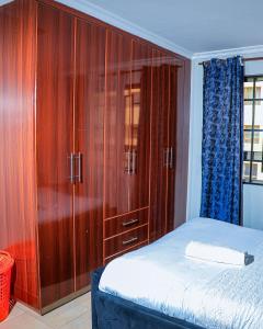a bedroom with a bed and a large wooden cabinet at Greatwall in Athi River