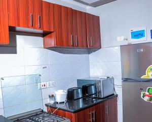 a kitchen with wooden cabinets and a microwave and a refrigerator at Greatwall in Athi River +6 photos