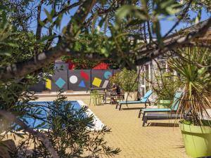 a patio with chairs and tables and plants at greet Hotel Marseille Provence Aéroport in Vitrolles