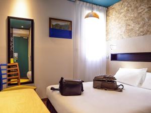 a hotel room with a bed with a bag on it at greet Hotel Marseille Provence Aéroport in Vitrolles +46 photos