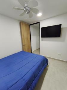 a bedroom with a blue bed and a flat screen tv at Comfort and convenience for your family stay in Ibagué