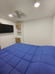 a bedroom with a blue bed and a flat screen tv at Comfort and convenience for your family stay in Ibagué