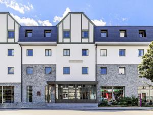 een groot wit gebouw met een blauw dak bij Mercure Han-sur-Lesse in Han-sur-Lesse