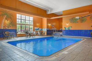 フレデリクトンにあるBest Western Plus Fredericton Hotel & Suitesのテーブルと椅子付きの客室内の大きなプール