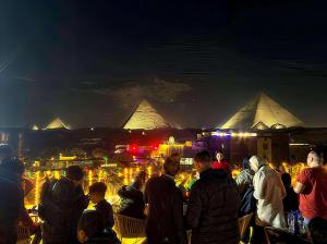 a crowd of people looking at the pyramids at night at 3 PYRAMiDS HUT HOTEL in Cairo