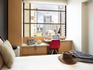 une chambre avec un lit, un bureau et une fenêtre dans l'établissement ibis Sydney World Square, à Sydney 51 autres photos