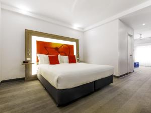 une chambre avec un grand lit avec des oreillers rouges dans l'établissement Novotel Darwin CBD, à Darwin 95 autres photos