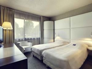 una camera d'albergo con due letti e una finestra di Mercure Brive a Ussac Altre 39 foto