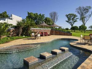 Una piscina con mesas y sillas en un patio. en Founders Lodge by Mantis, en Paterson