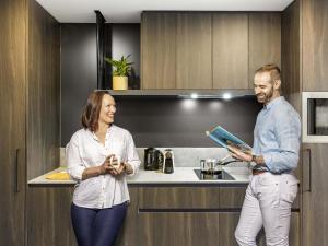 a man and a woman standing in a kitchen at The Sebel Canberra Campbell in Canberra +43 photos