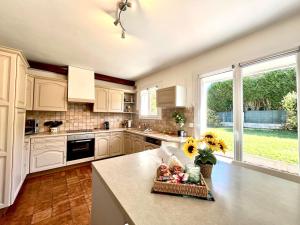 a kitchen with white cabinets and a table with sunflowers at La Bichonne, familial, golf et commerces à pied in Quéven