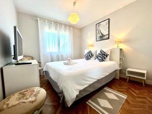 a bedroom with a large white bed and a television at La Bichonne, familial, golf et commerces à pied in Quéven