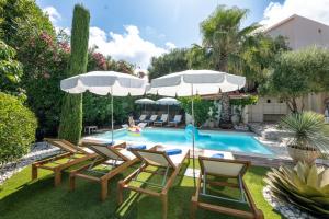 un patio trasero con una piscina con sillas y sombrillas en Azurenting - Villa 5 chambres - Juan-les-pins, en Antibes 24 fotos más