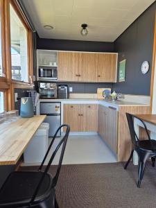 a kitchen with wooden cabinets and a table and chairs at McKerrow St - 2 in Te Anau