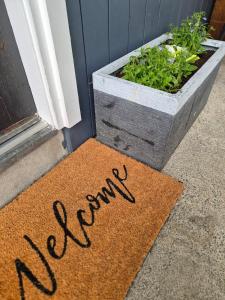 a welcome mat in front of a window with a plant at McKerrow St - 2 in Te Anau