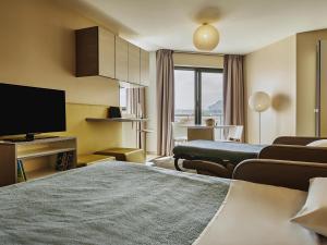 a hotel room with a television and a living room at AppartHotel Mercure Paris Boulogne in Boulogne-Billancourt