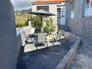 a patio with a table and chairs and an umbrella at Ninho's Sea View in Ribeira Brava
