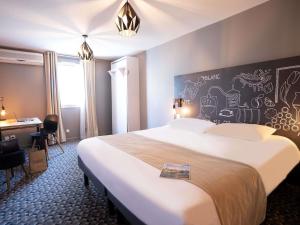 a hotel room with a large bed and a desk at Ibis Styles Cognac in Châteaubernard +114 photos