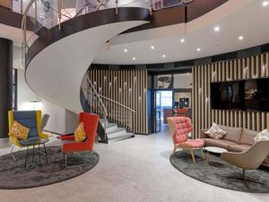 a lobby with colorful chairs and a staircase at Fora Hotel Hannover by Mercure in Hannover