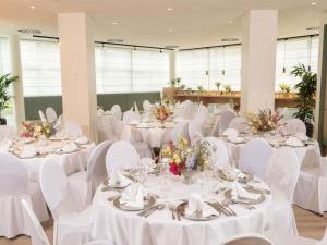 a banquet hall with white tables and white chairs at Fora Hotel Hannover by Mercure in Hannover
