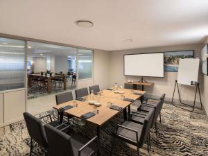 a conference room with a table and chairs and a whiteboard at Mercure Sydney Manly Warringah in Sydney