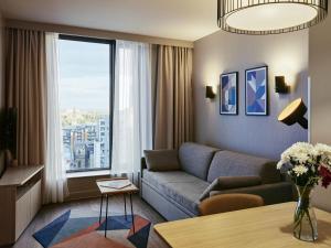 Una sala de estar con un sofá y una ventana grande. en Aparthotel Adagio Glasgow Central, en Glasgow