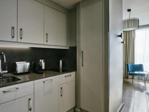 una cocina con armarios blancos y una silla azul en Aparthotel Adagio Glasgow Central, en Glasgow 66 fotos más