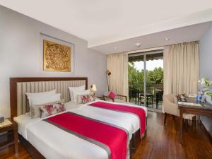 a bedroom with a bed and a desk and a window at Novotel Goa Resort & Spa Candolim in Candolim