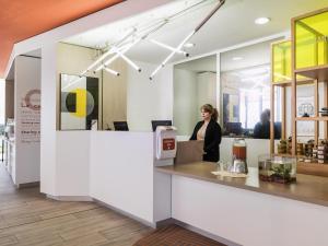 una mujer parada en un mostrador en una cafetería en Aparthotel Adagio Access Paris Massy Gare, en Massy