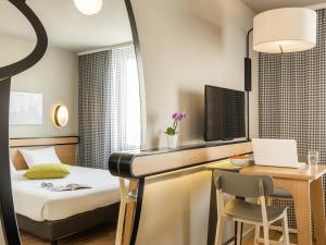 Una habitación de hotel con una cama y un escritorio con una computadora. en Aparthotel Adagio Access Paris Massy Gare, en Massy
