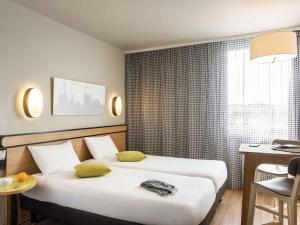 Una habitación de hotel con dos camas, una mesa y un escritorio. en Aparthotel Adagio Access Paris Massy Gare, en Massy 62 fotos más