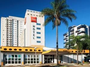 a hotel with a palm tree in front of a building at Ibis São Carlos in São Carlos