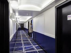 a woman standing in a hallway with blue tiles at Mercure Paris la Défense Grande Arche in Nanterre