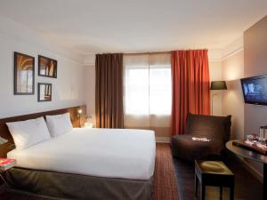 a hotel room with a white bed and a couch at Mercure Paris la Défense Grande Arche in Nanterre +37 photos