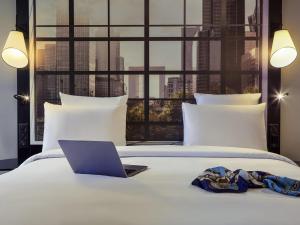 a laptop on a bed with a view of a city at Mercure Paris la Défense Grande Arche in Nanterre