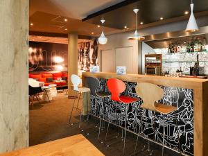a bar with red and white stools in a restaurant at ibis Nancy Centre Gare et Congres in Nancy