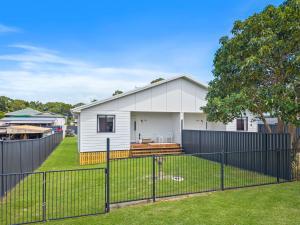 a white house with a fence in a yard at Roys Place by Discover Stradbroke in Amity Point