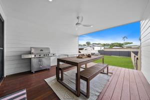 a kitchen with a wooden table and a grill at Roys Place by Discover Stradbroke in Amity Point