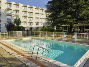 a large swimming pool in front of a building at Novotel Massy Palaiseau in Palaiseau