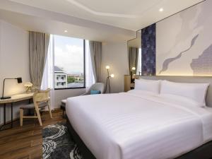 ラヨーンにあるNovotel Rayong Star Convention Centreの大きなベッドと机があるホテルの部屋 +82枚の写真