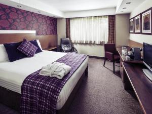 a hotel room with a bed and a desk at Mercure Swansea Hotel in Swansea