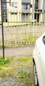 un coche blanco estacionado junto a una valla en Descansa en el sur, en Puerto Montt