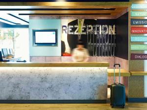 a person walking past a counter with a suitcase at ibis budget Zurich City West in Zürich