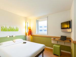 a bedroom with a bed and a desk with a laptop at ibis budget Zurich City West in Zürich