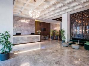 a lobby with a reception desk and potted plants at Tbilisi Philharmonic Hotel by Mercure in Tbilisi City