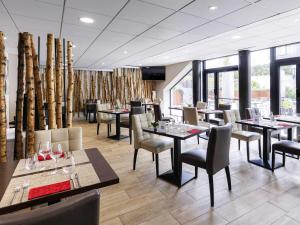 a dining room with tables and chairs and windows at Mercure Bale Mulhouse Aeroport in Blotzheim
