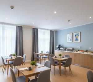 Un comedor con mesas y sillas y una cocina. en Yenibir Apart, en Alejandreta