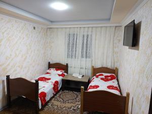 a room with two beds and a table and a tv at Elit Hotel in Mingachevir